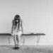 girl sitting head down on bench in front of tile wall