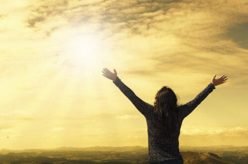 woman standing with arms outstretched in the sun