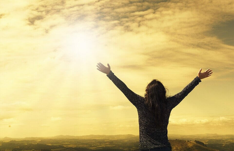 woman standing with arms outstretched in the sun